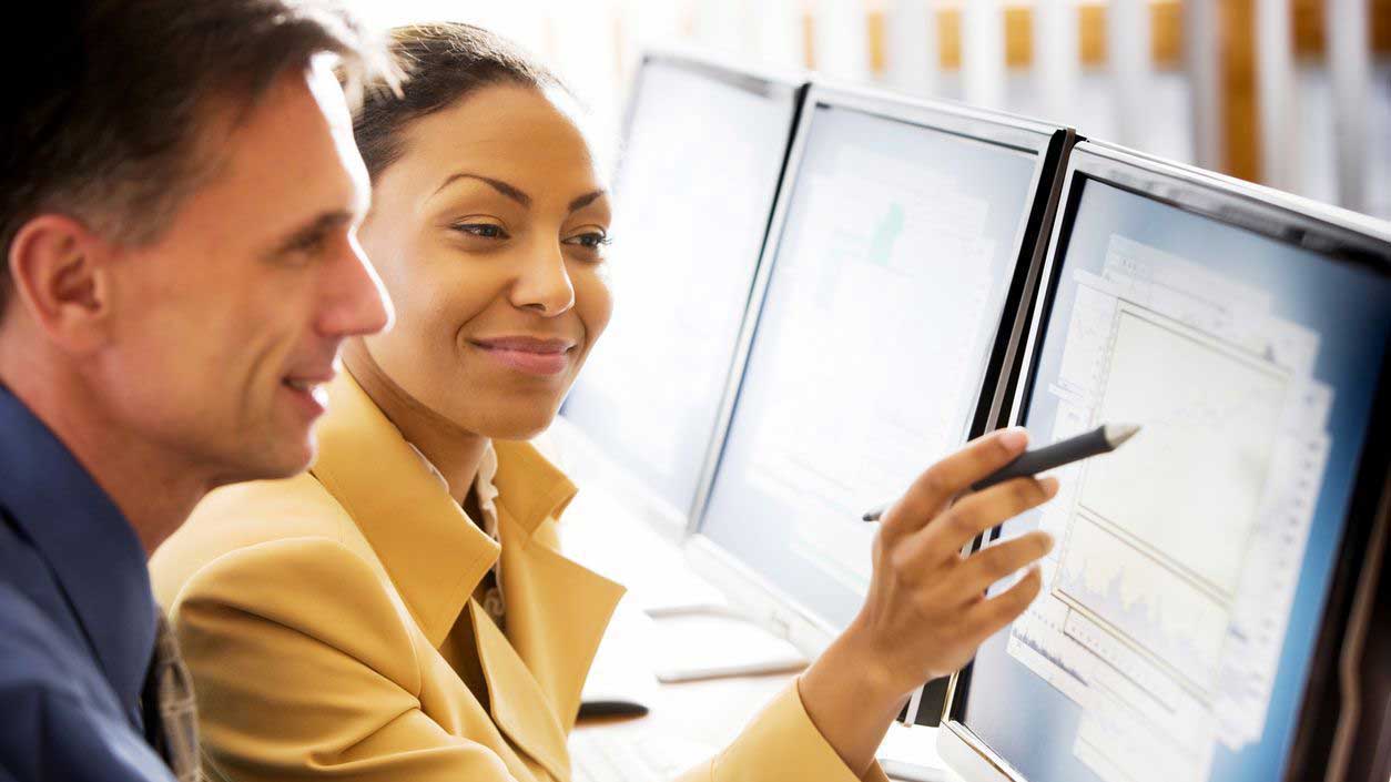 Man and woman looking at a computer screen and the woman is pointing to an image on the screen.